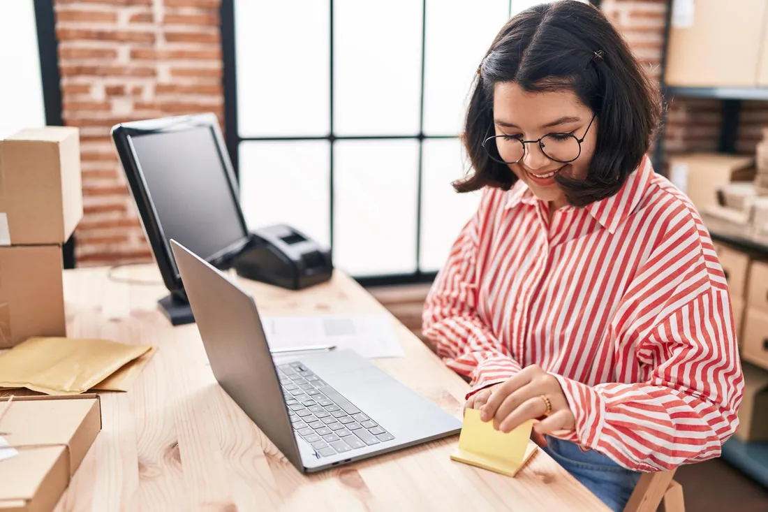 Vendedora anotando informações ao lado do notebook