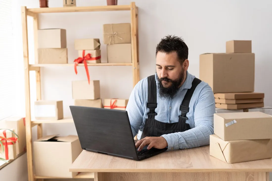 Vendedor no notebook cercado de caixas de pedidos